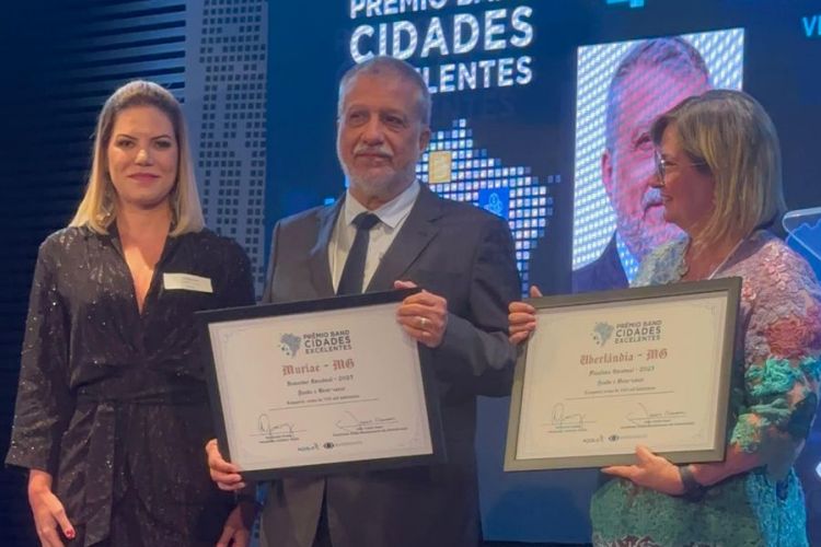Momento de orgulho: o prefeito Dr. Marcos Guarino recebe o Prêmio Band Cidades Excelentes em uma cerimônia repleta de aplausos e celebração.
